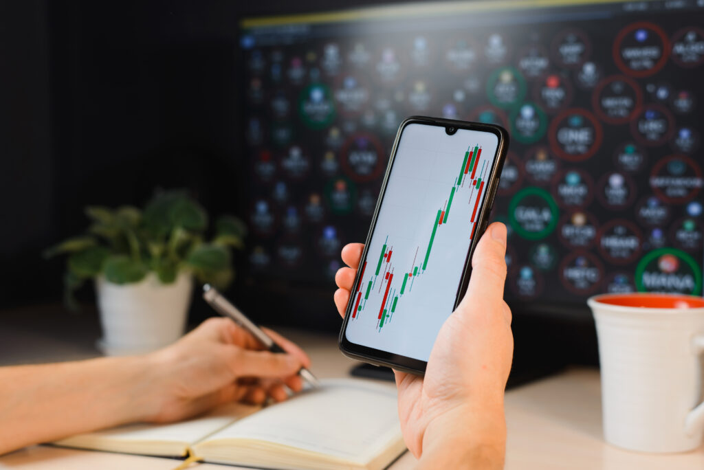 Hand houdt smartphone met grafieken - Trading Journal