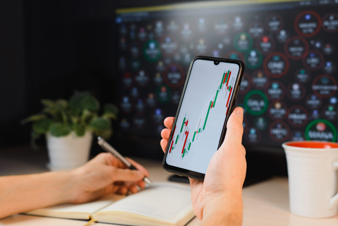 Hand houdt smartphone met grafieken - Trading Journal